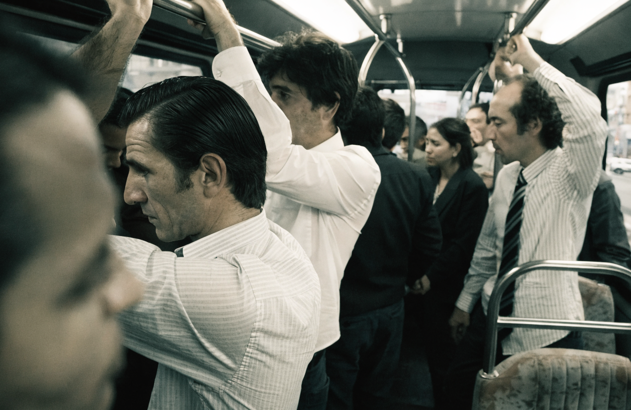 Empleados de pie, apretados e incómodos dentro de un bus tradicional en hora pico